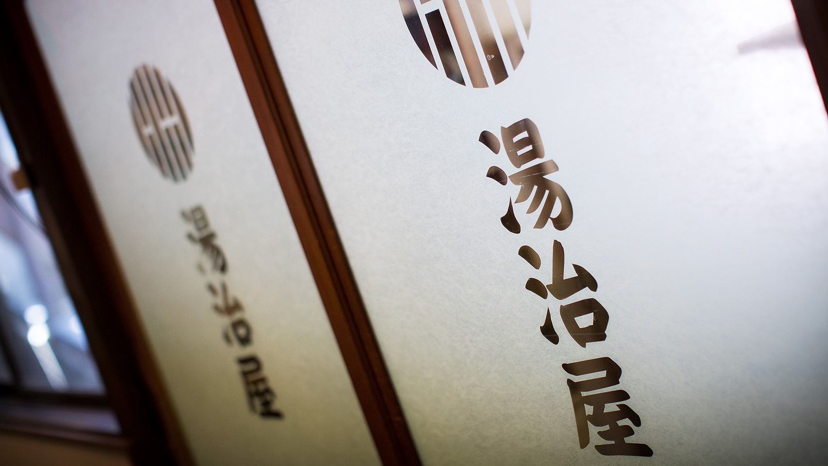 昔ながらのガラス扉に湯治屋のロゴ