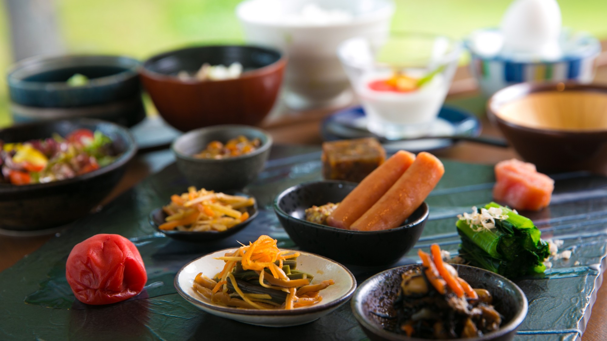 【和朝食】種類豊富な和総菜の小鉢が並ぶ。山形県遠山産つや姫米の炊き立てごはんと自慢のおかずたち