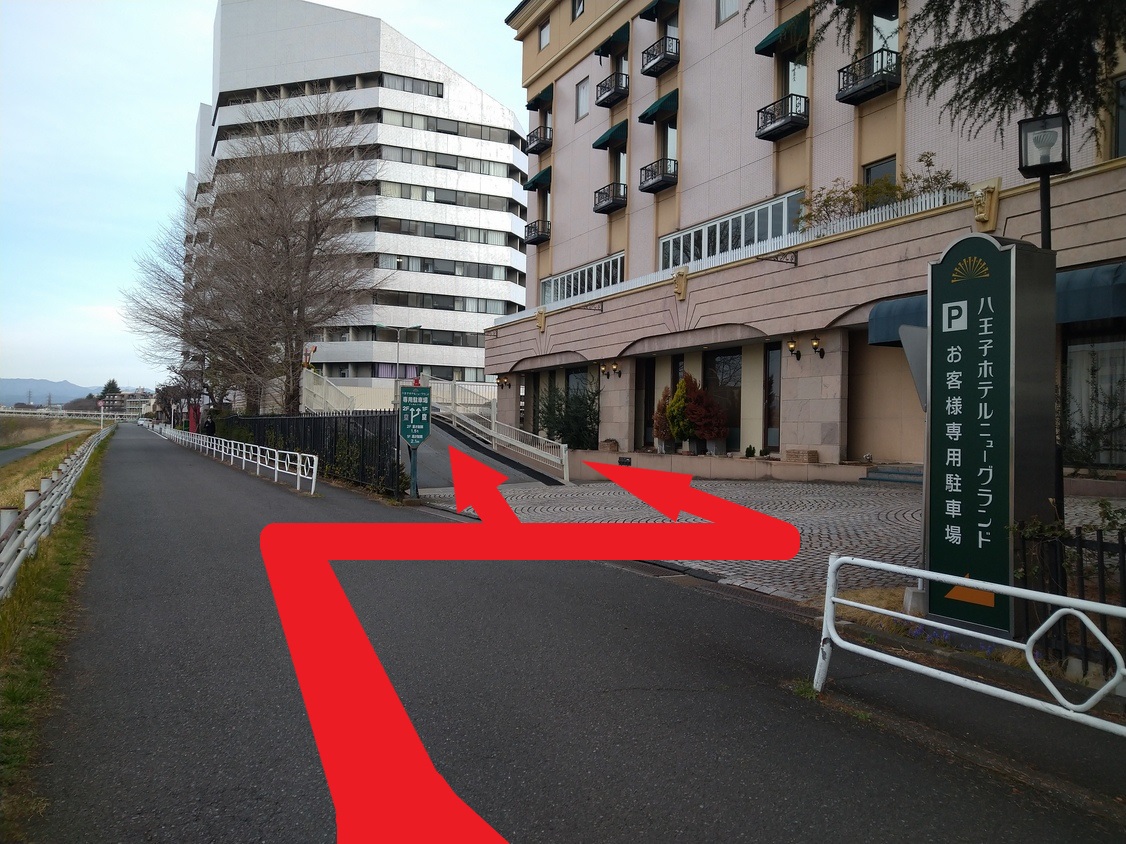 川沿いの道を進みますとホテル正面入り口がございます。右矢印方向に1階・左に2階無料駐車場がございます