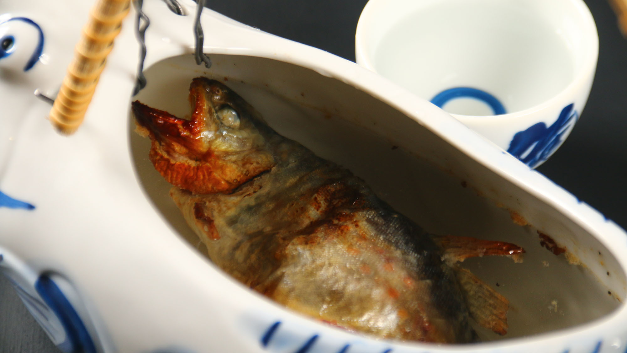 岩魚の骨酒岩魚の塩焼きにアツアツの酒を注ぐ岩魚の旨味が出た琥珀色の酒