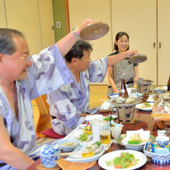 貝のホウロク焼きの蓋を開けるお客様