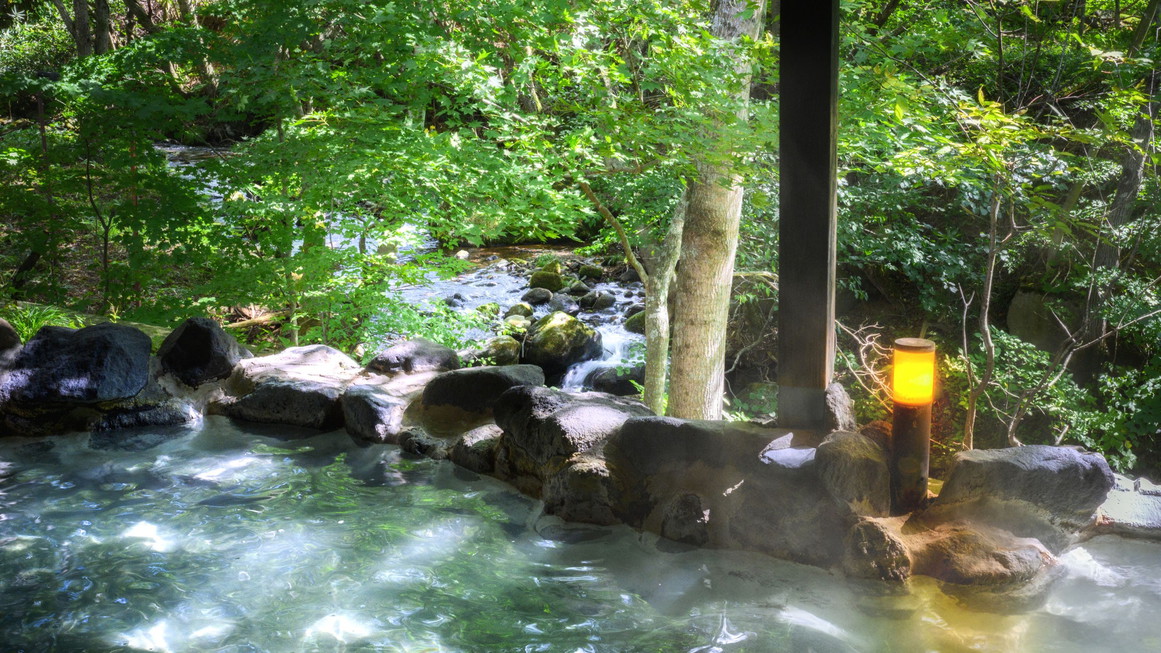 【かわせみの湯／大露天風呂】目の前には渓流が流れ、川のせせらぎを聞きながらご入浴いただけます。