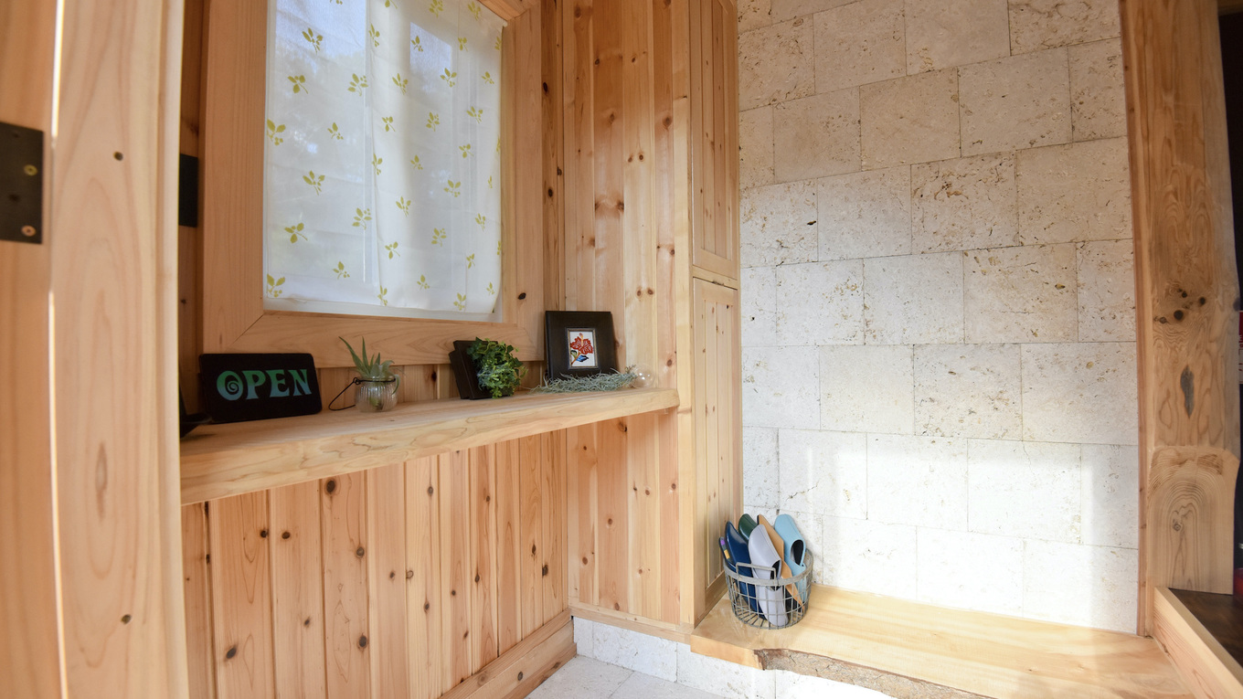 玄関／杉や檜の木材と沖縄ならではの琉球石灰岩を組み合わせた壁