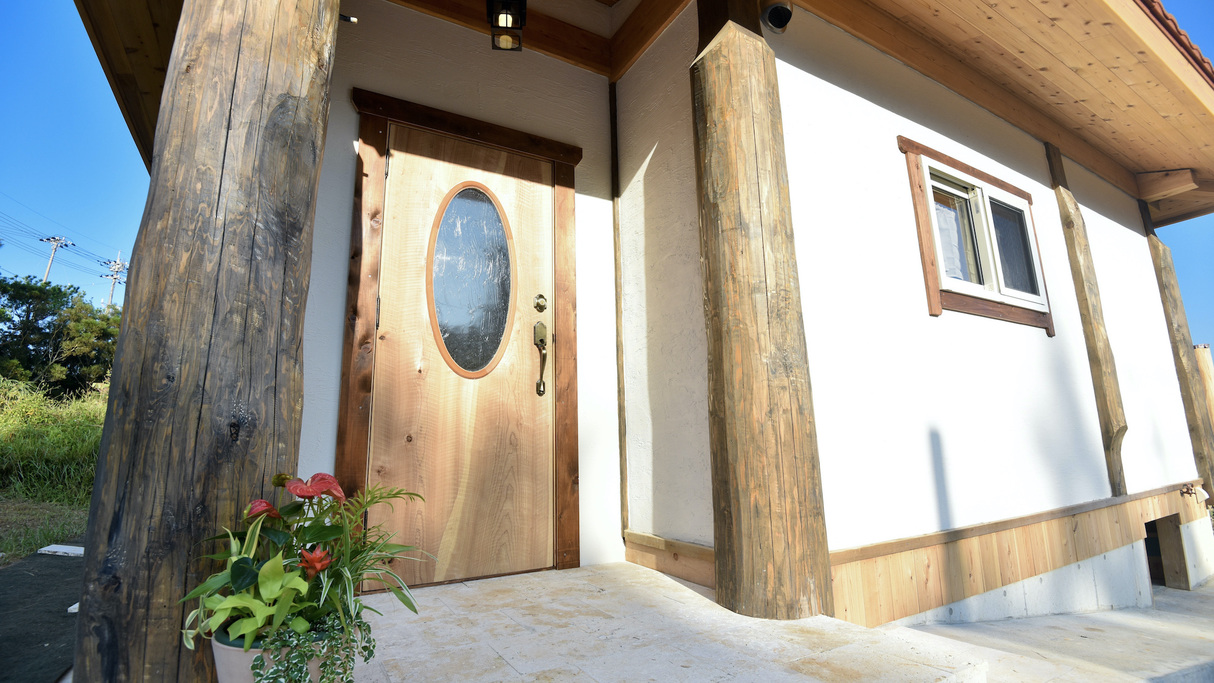 玄関／外壁は杉や檜の丸太と琉球漆喰の組み合わせ
