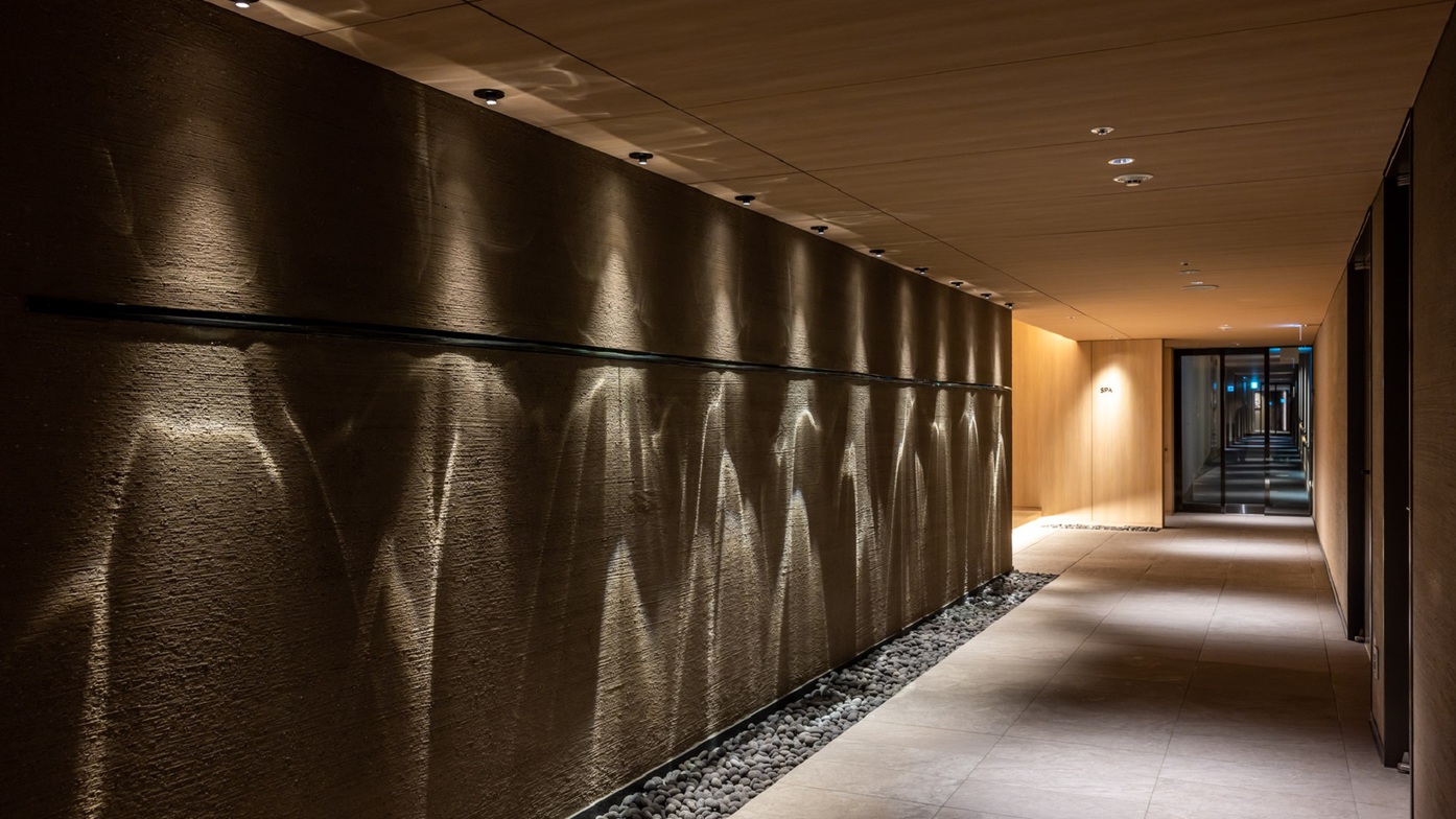 【大浴場エントランス】大浴場までの廊下は趣のある石と光に包まれた落ち着いた雰囲気となっております。