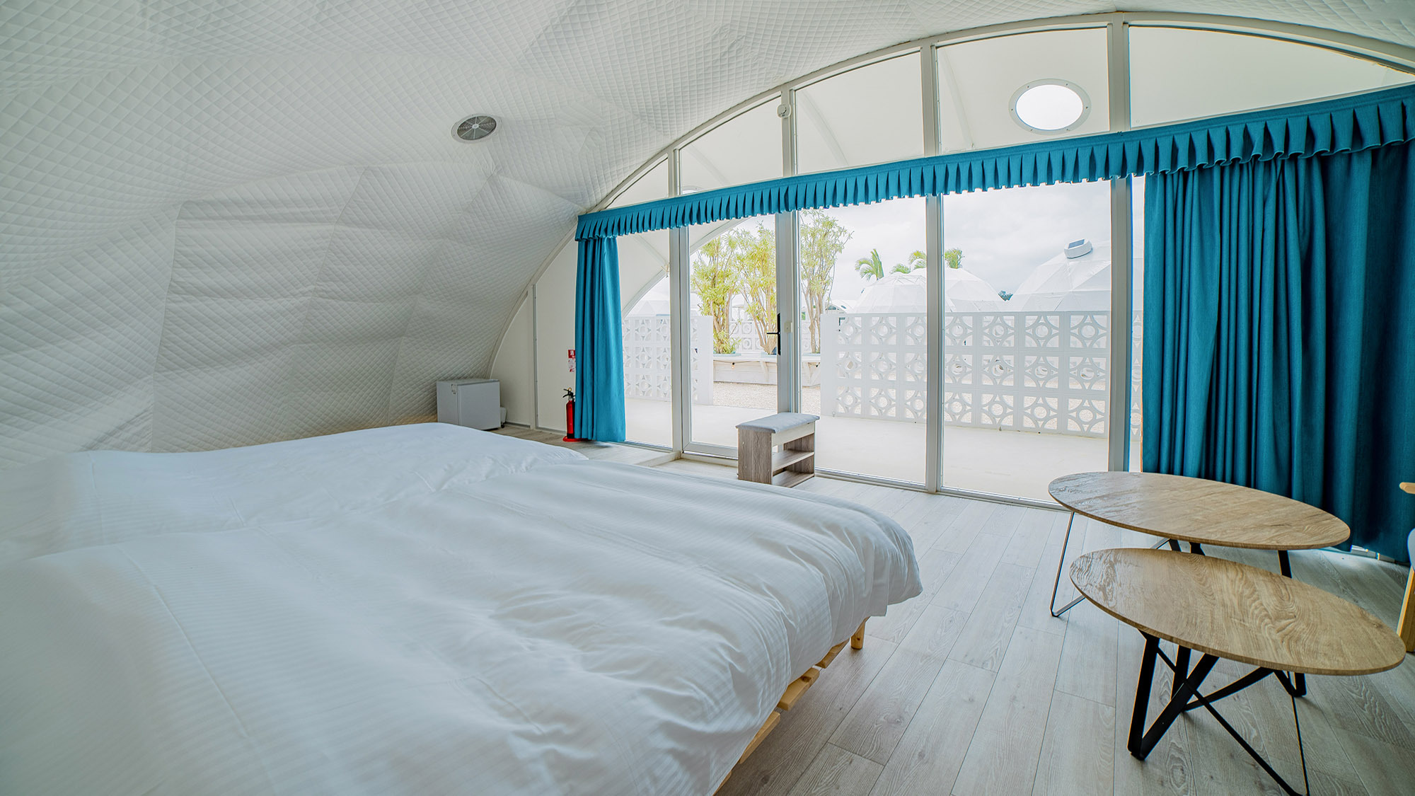 ・【スーペリアドーム】白いベッドにマリンブルーのカーテンが印象的