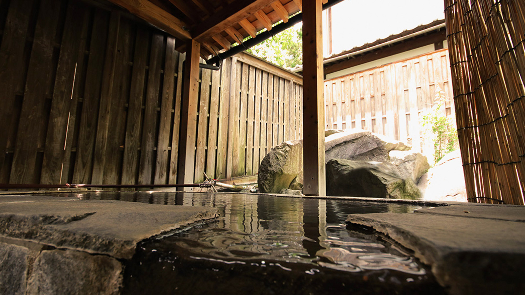 ・【男湯内風呂】木と石に囲まれた半露天風呂。源泉かけ流しの湯でリラックスできます