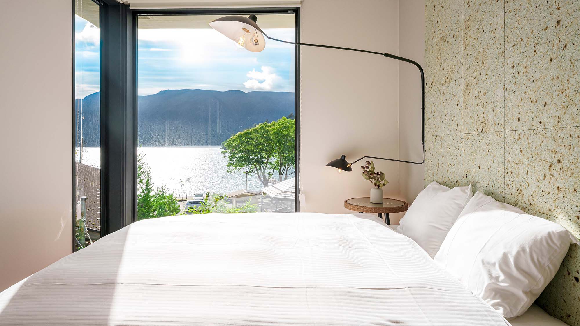 ・【寝室】窓からは芦ノ湖と周囲の山々を一望。新しい一日の始まりを湖の煌めきと共に