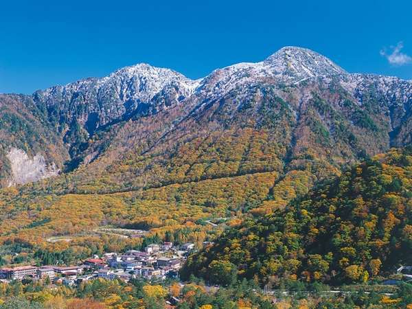 秋の奥飛騨温泉郷・平湯峠。冠雪の山頂と紅葉のコントラストが美しい