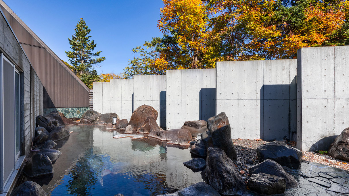 【露天風呂】趣きある岩造りの温泉を、秋は周辺の木々が鮮やかに彩ります。