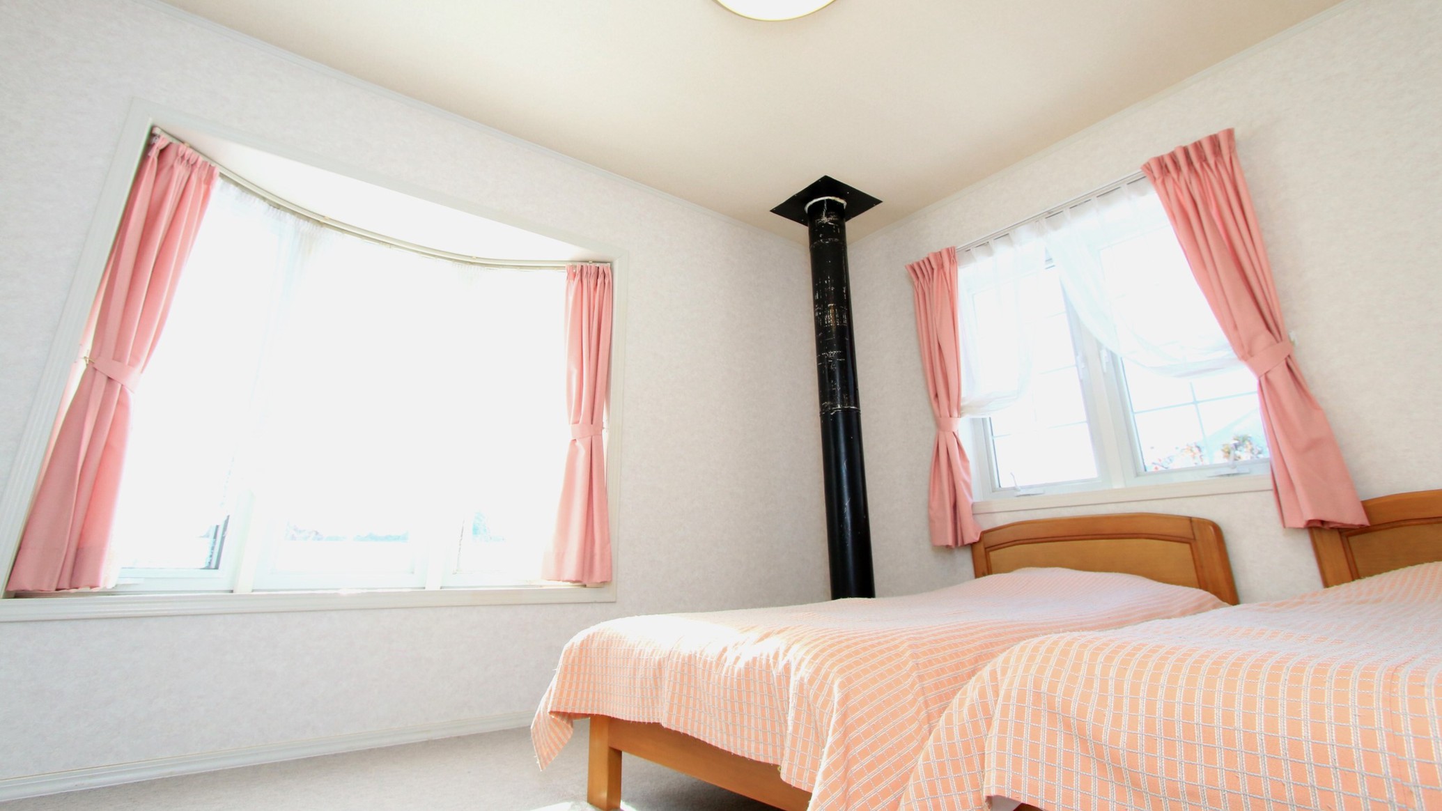 【客室】ツイン１階の薪ストーブの煙突がお部屋を温めてくれる客室