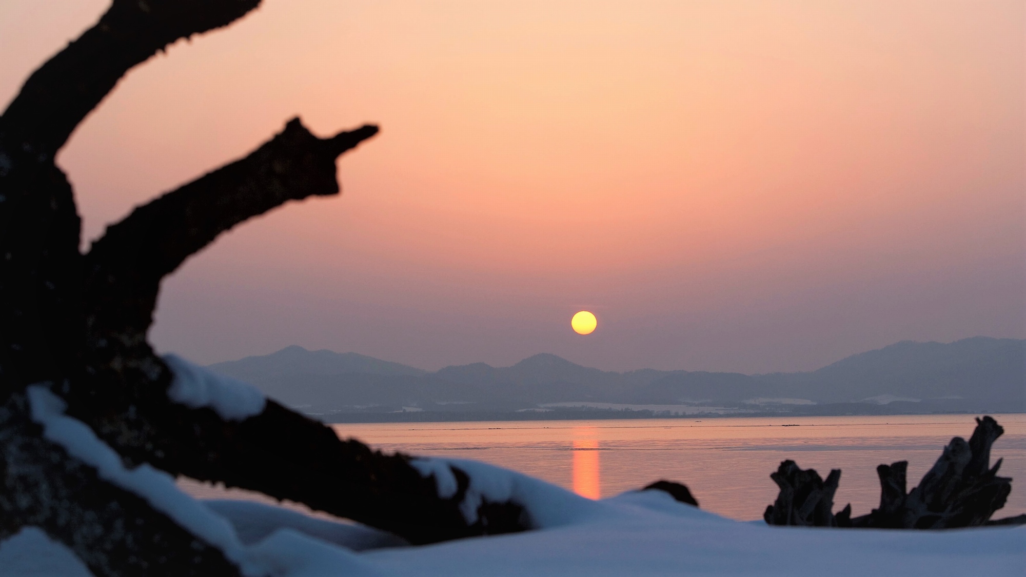 【サロマ湖の夕日（冬）】雲のない日は、オホーツクに沈む夕日と一面を染める美しいグラデーションの空。