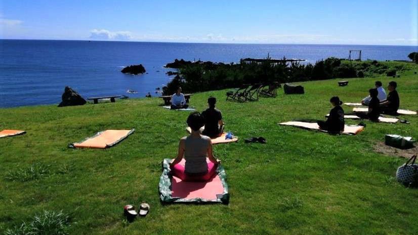 芝生の上で心地よい潮風を浴びながらの朝ヨガ